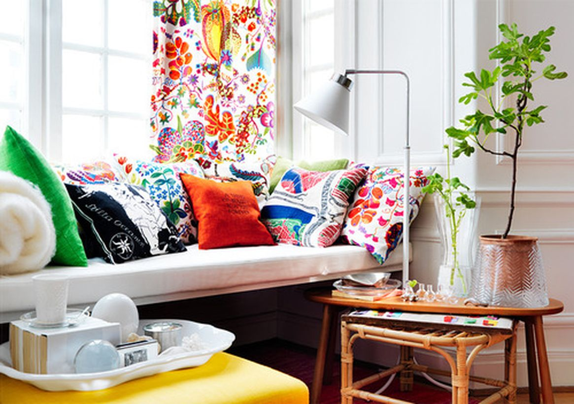 An amazing design of the living room with the splash of the color of the pillow, the spark of certain colors, white walls, wooden tables, rattan chairs that make guests more happy