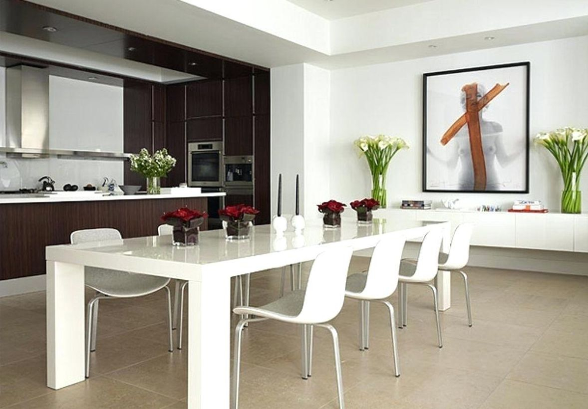 An amazing modern white dining room with white walls, white rectangular tables, white chairs, and white flowers to create room more beautiful