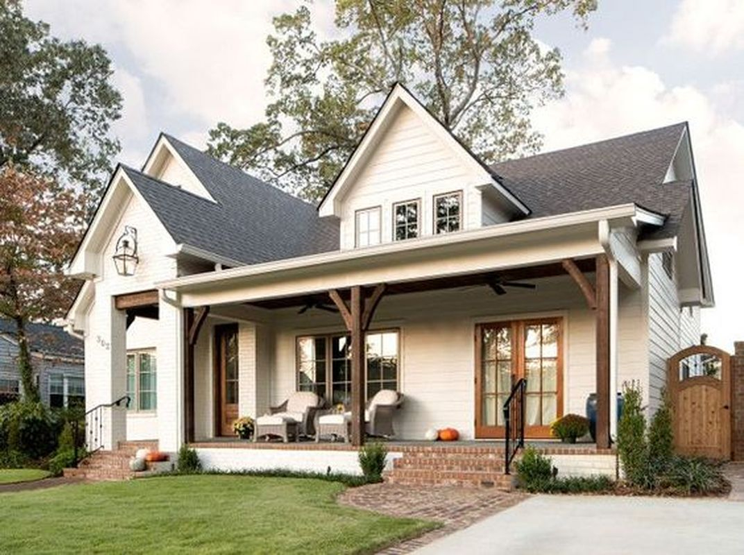 Simple farmhouse design elements in this exterior are dark roof, white siding, white trim, wood beam porch and doors