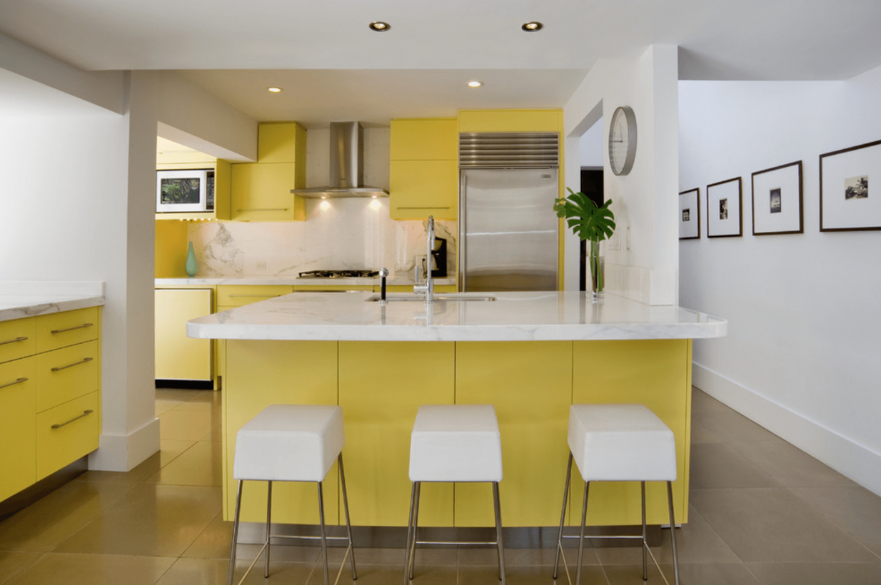 Stunning yellow and white kitchen with yellow cabinet storage, white chairs, white walls, brown floors