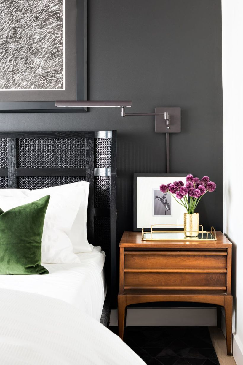 The black accent wall bedroom with a big wall art, a night stand to store a house plant and a gallery