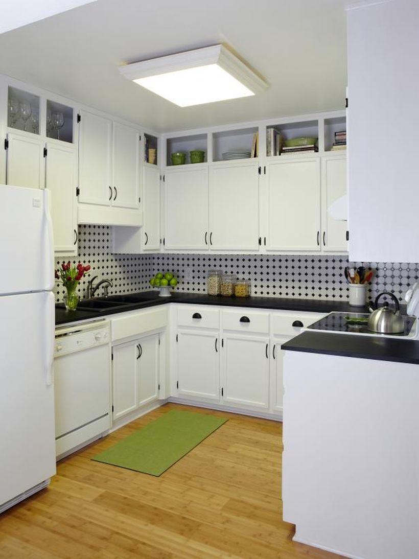 A gorgeous white kitchen design with white kitchen storage cabinets, a white refrigerator, a black granite table, and white backsplash polka dot black pattern