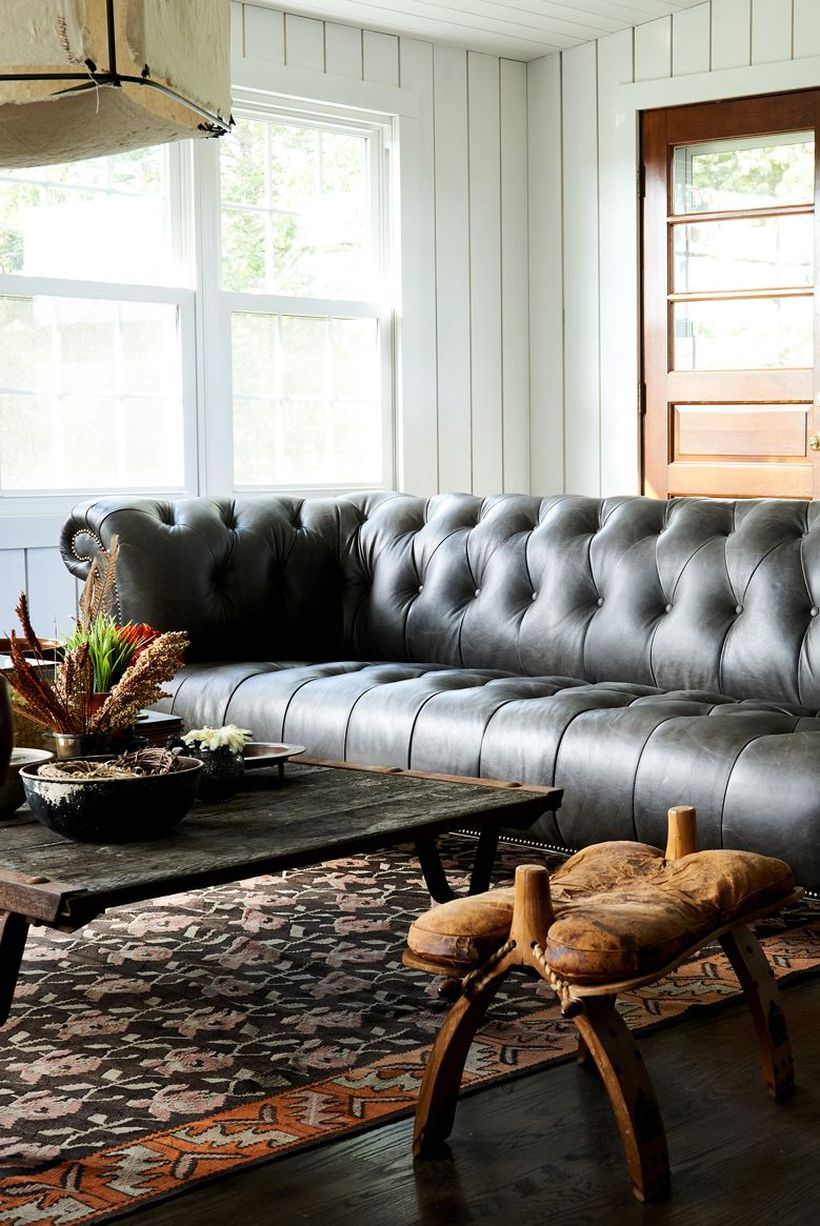 A stunning farmhouse living room decor ideas with an antique wooden furniture, white wooden pallet walls, white big windows, and house plants to create beautify