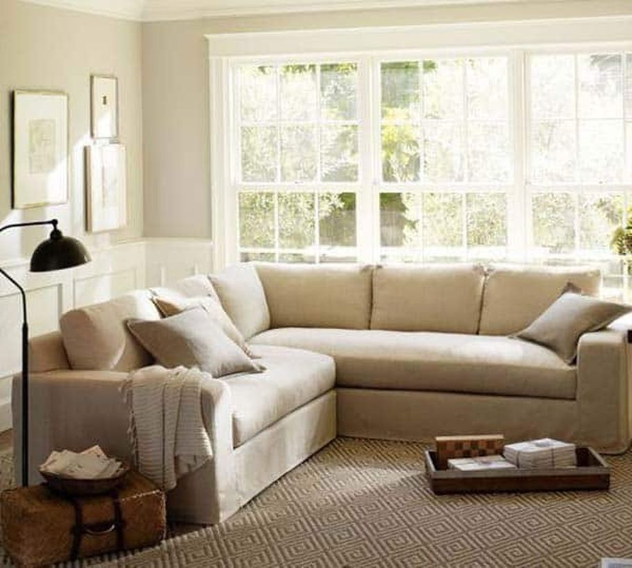 A beautiful small living room design with white and light gray walls, a light gray leeter l sofa, big windows, a rattan basket, and floor lamp