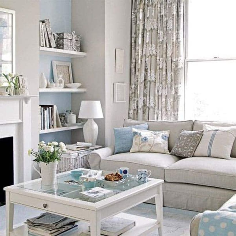 A cozy living room decor ideas with pink sofas, a big window, a pattern flowers curtain on pink colour, wooden hanging racks, a coffee table, rattan basket to place table lamp