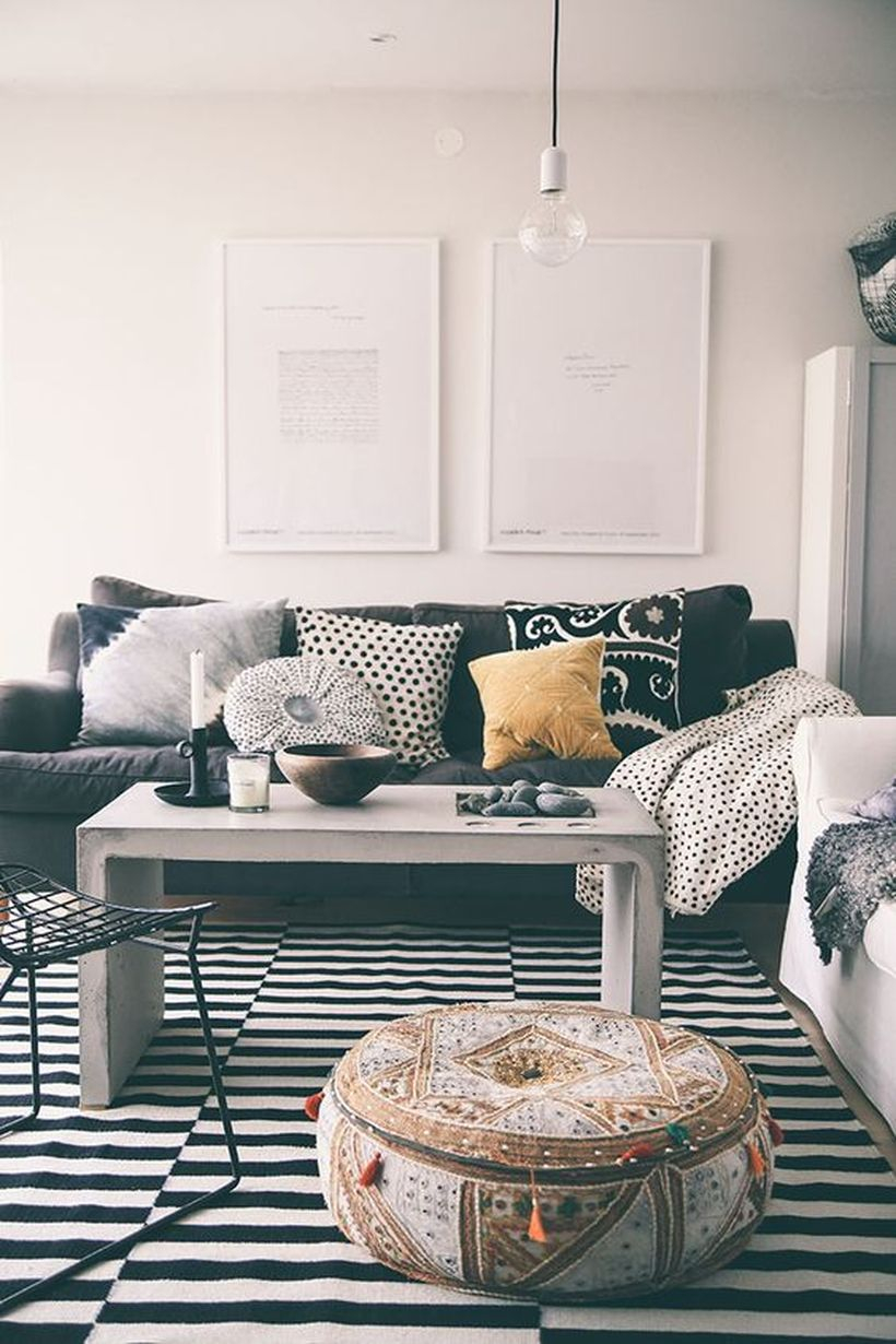 A gorgeous black and white living room design with white walls, a striped patterned carpet, black and white sofas