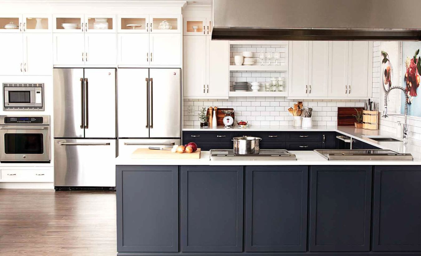 A modern black and white kitchen design with black and white kitchen cabinet storages, white splash pattern brick walls, white hanging rack in the middle of cabinet