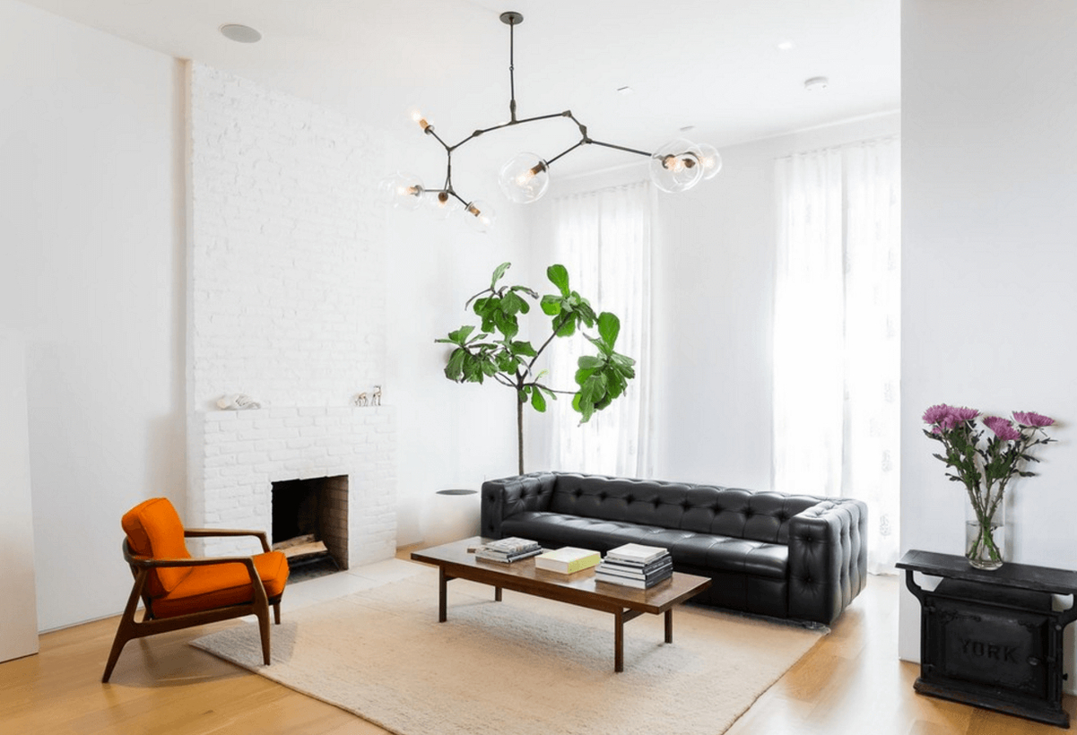 A modern farmhouse living room design with white walls, a white fireplace, white overlay curtains, a wooden coffee table, decorative lighting, house plants to create fresh room