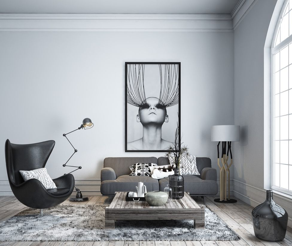 A modern living room monochrome color design with white and grey carpet, big painting on the walls, grey sofa, wooden coffee table, a house plant, a black jars, decorative lighting