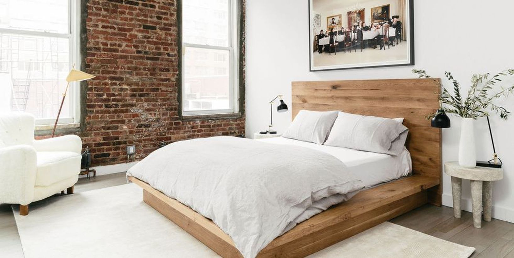 A sleek wooden bed frame and brick walls to create a cozy in the minimalis space