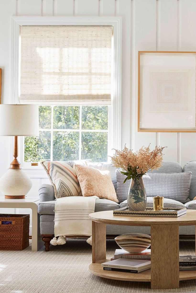 A small living room design with white walls, a large window, a grey sofa, a round coffee table, and a house plant to create a cozy