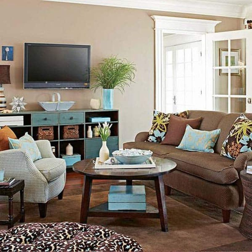 An amazing living room decor ideas with beige walls, white and brown sofas, a storage cabinet to put some accessories, a table lamp, hanging tv on the walls, a round wooden coffee table, and house plants