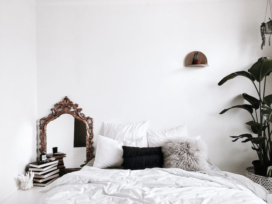 An awesome small bedroom with a hanging rack to put some house plant, a mirror at the corner, and decorative plants on the beside of bedroom to create fresh room