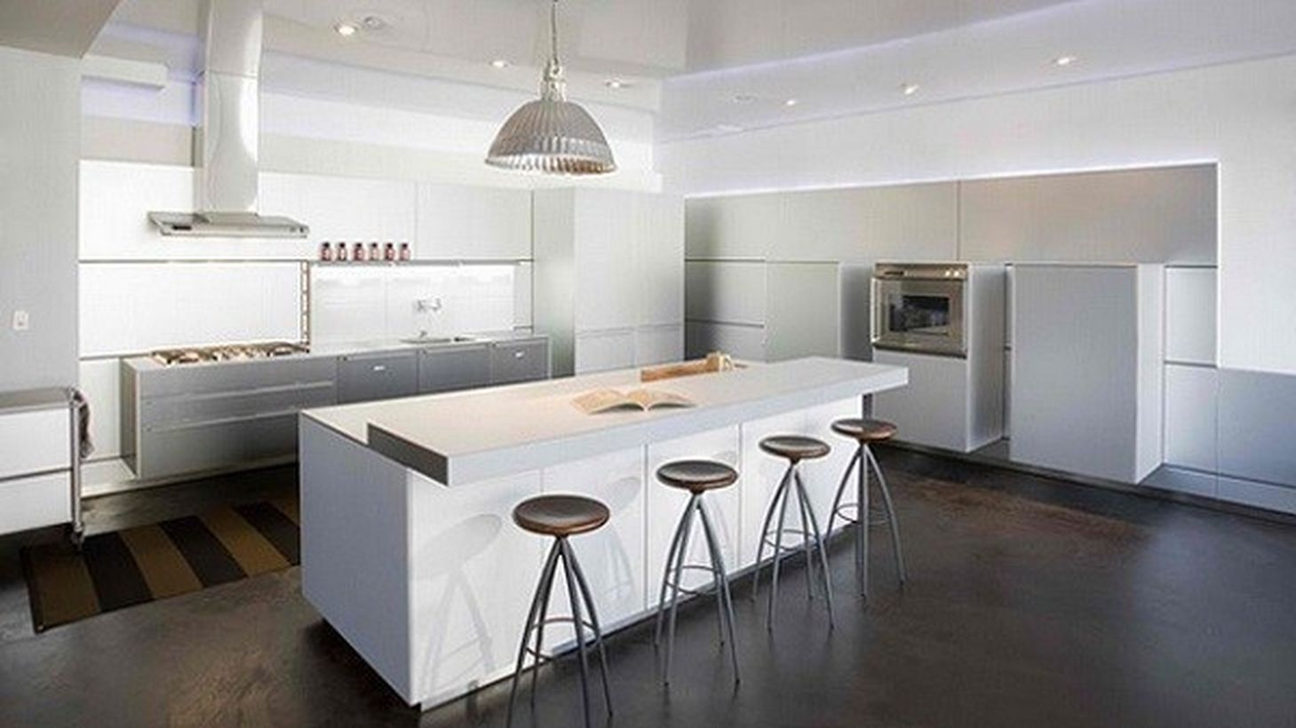 An impressive modern white kitchen design with white kitchen cabinet storages, a large white kitchen island, and decorative lighting to create good light