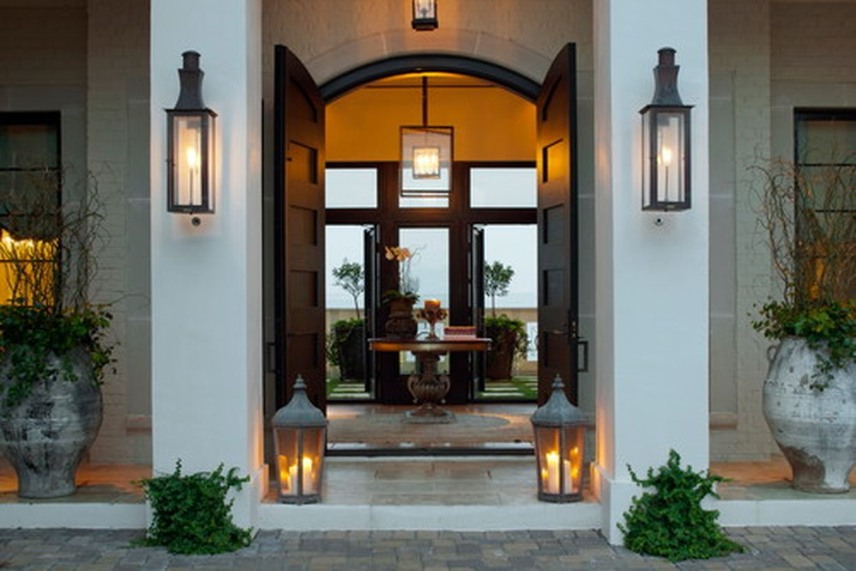 An amazing farmhouse porch ornament with large white potted plants, candle lights, black light on the wall and hanging lamps