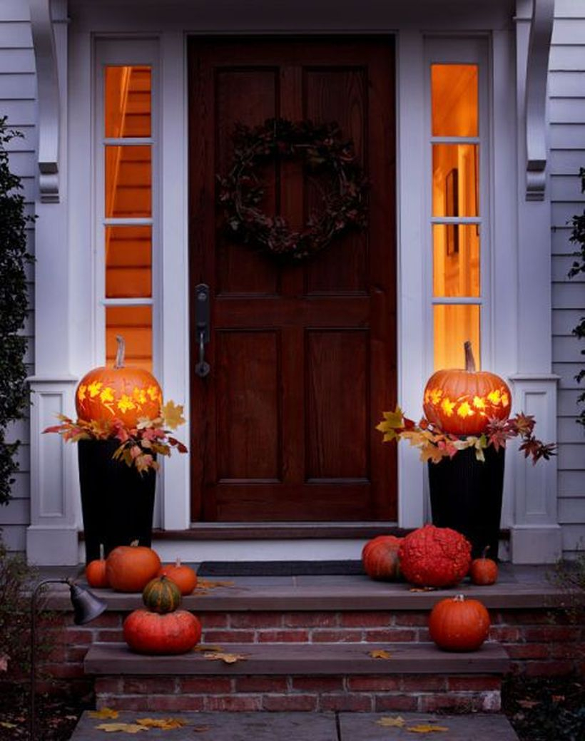 An amazing fall porch ideas with wreath, pumpkin planters and pumpkin light on the black pot