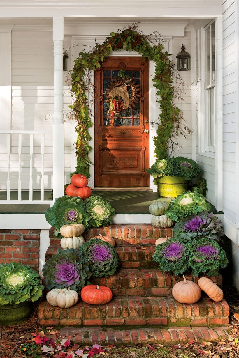 Beautiful front porch fall ideas with vines, wreath, pumpkins and green plants in pots