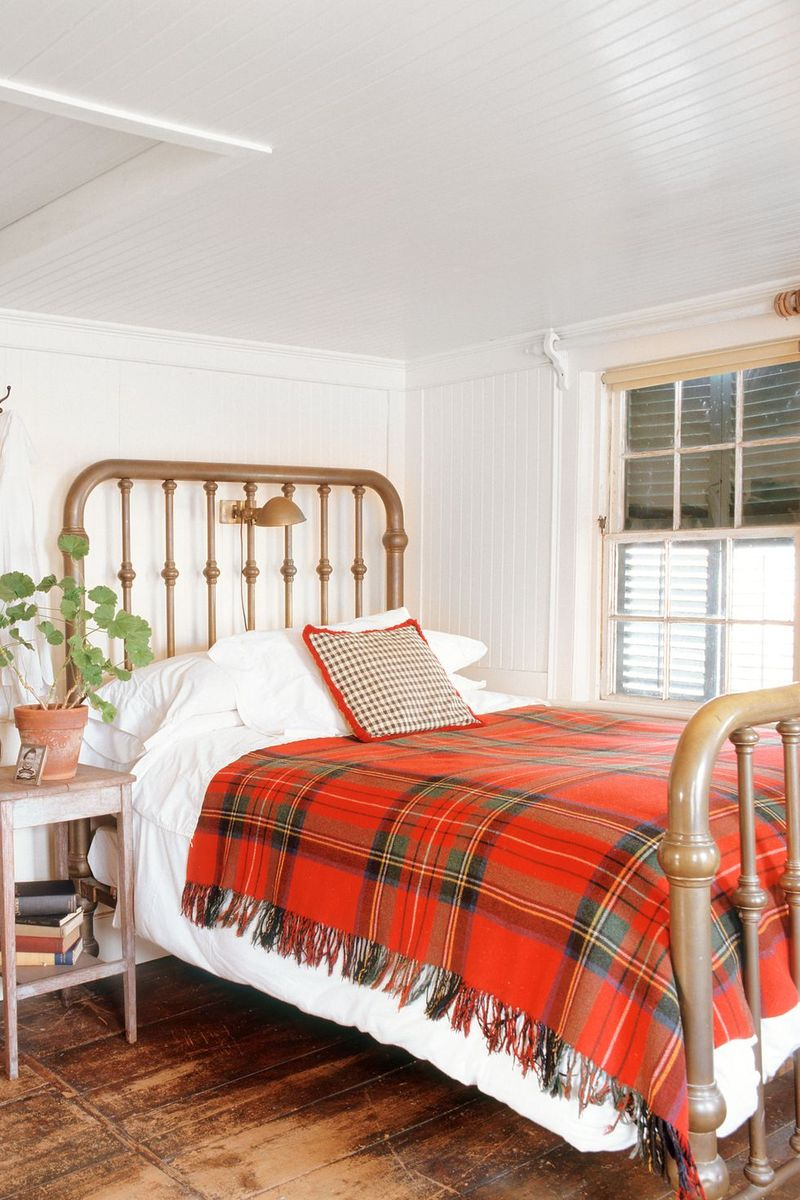 Fall bedroom decoration with a plaid blanket featuring red, orange, and golden hues to decorate this fall decoration