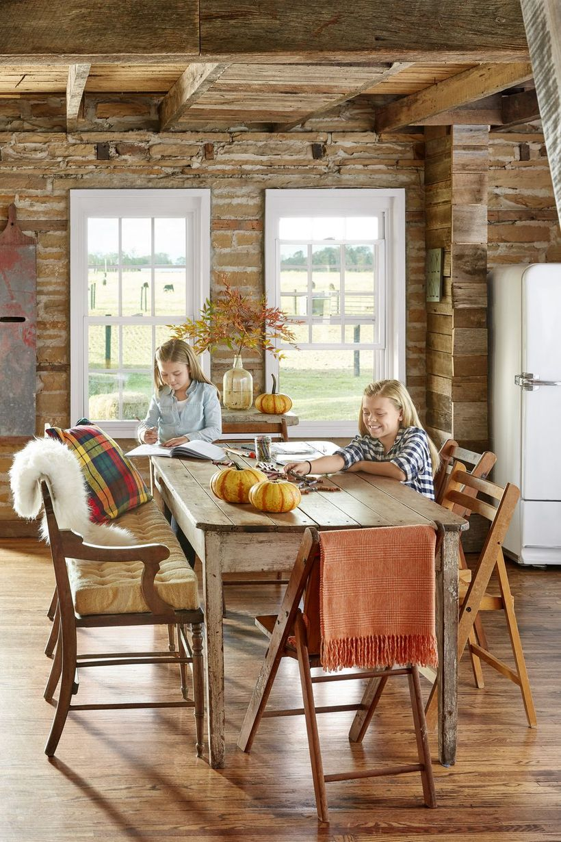 A comfortable indoor redecoration from summer to fall with blankets, pillows, and a cushioned bench will make everyone want to gather round the dinner table long after the food is gone.