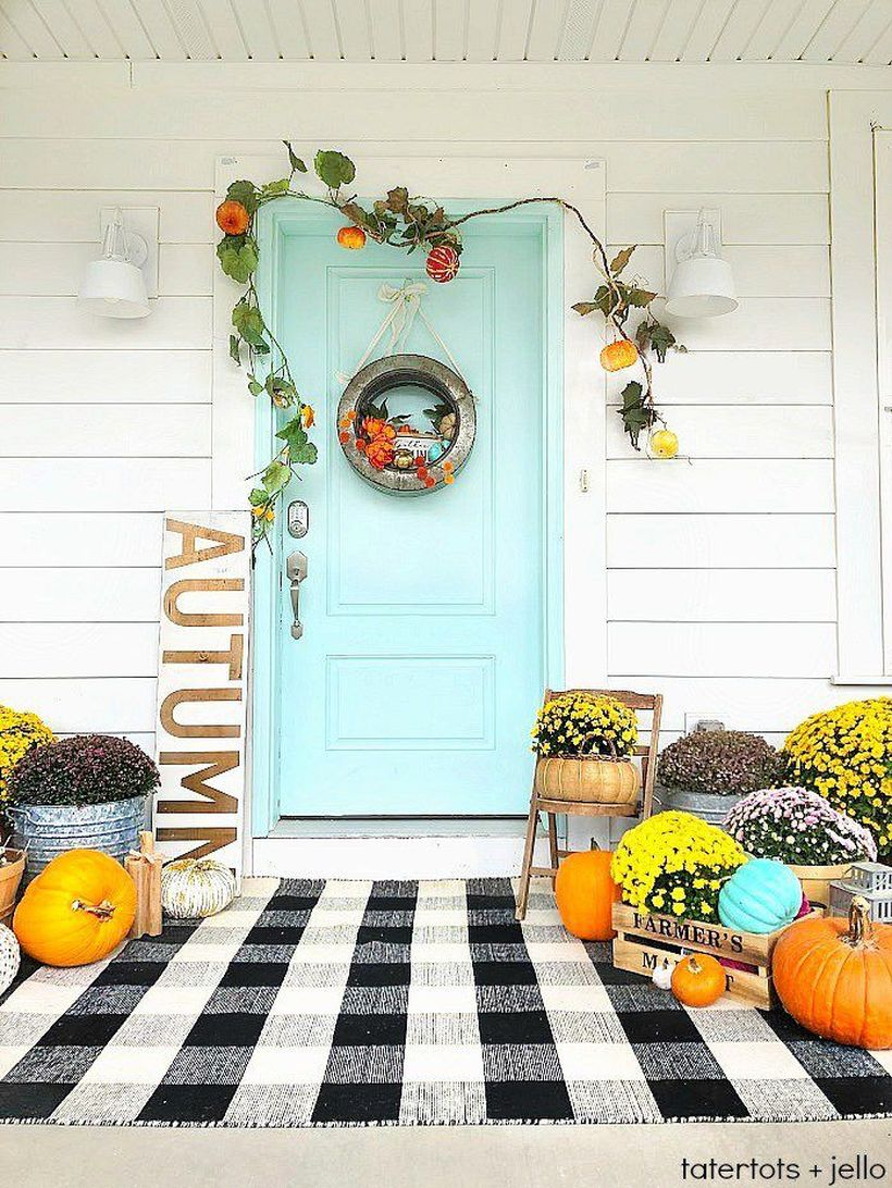 A creative outdoor redecoration from summer to fall with black and white plaid rug, some pumpkins, the rustic galvanized wreath and the overall beautiful color contrast.