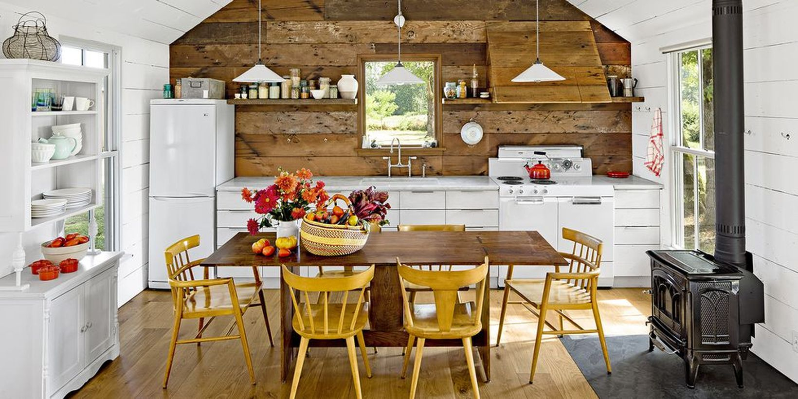 A stylish indoor redecoration from summer to fall with rustic white kitchen, apples, flowers, squash display on the table and golden yellow painted chairs also give this neutral kitchen homey