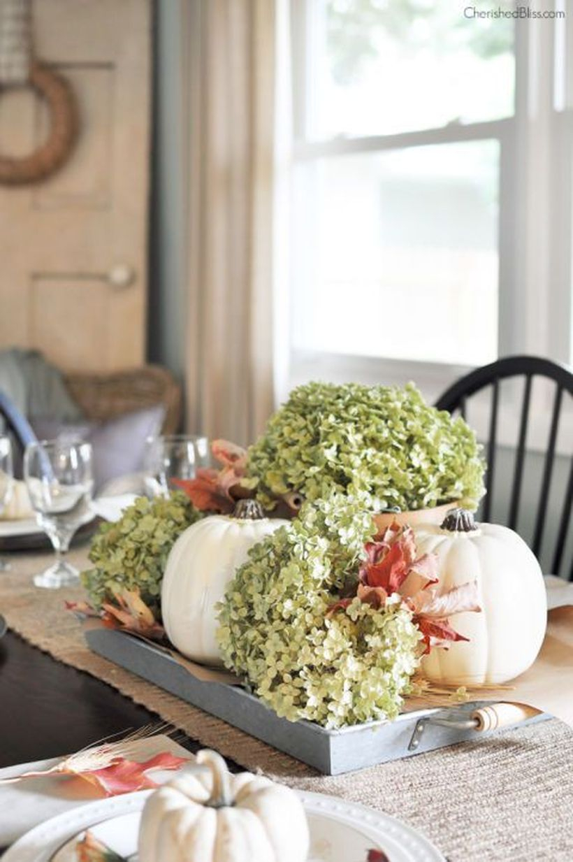 A unique indoor redecoration from summer to fall with white pumpkins, dried hydrangeas, and fallen leaves on a tray to create a portable centerpiece.