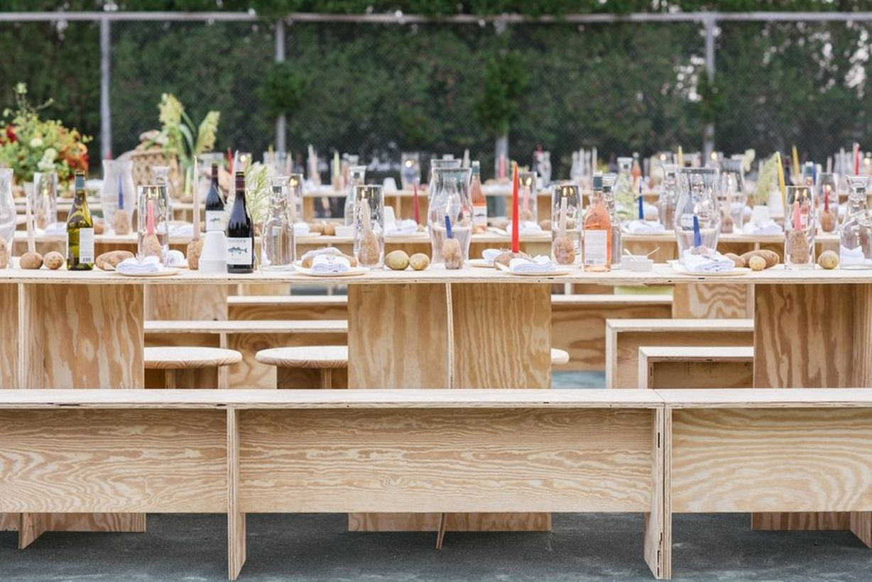 A unique outdoor table set for wedding with long wooden vinyl table, wooden vinyl chairs, glass bottles that will make your wedding look fantastic.