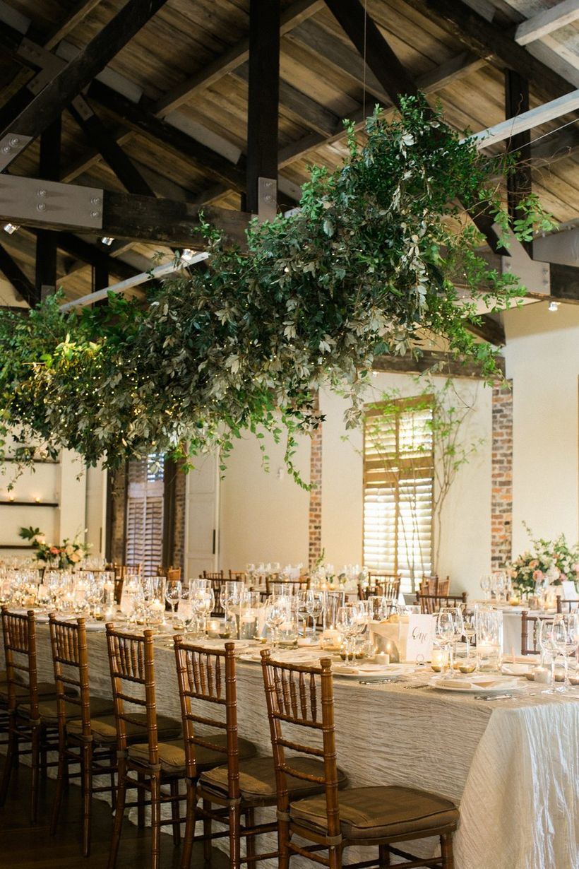 A wonderful indoor table set for wedding with long iron table, hanging greenery wedding greenery installation feels wild whimsical and a perfect.