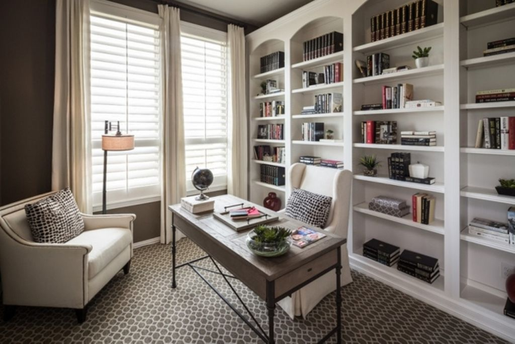 An awesome home office features wall bookshelves painted in white that features four spacious vertical sections which then has a horizontal parting
