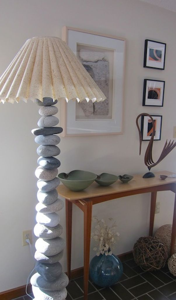 An awesome stone lamp combined with white walls, wooden table, wall gallery and dark floor to bringing natural elements into your home