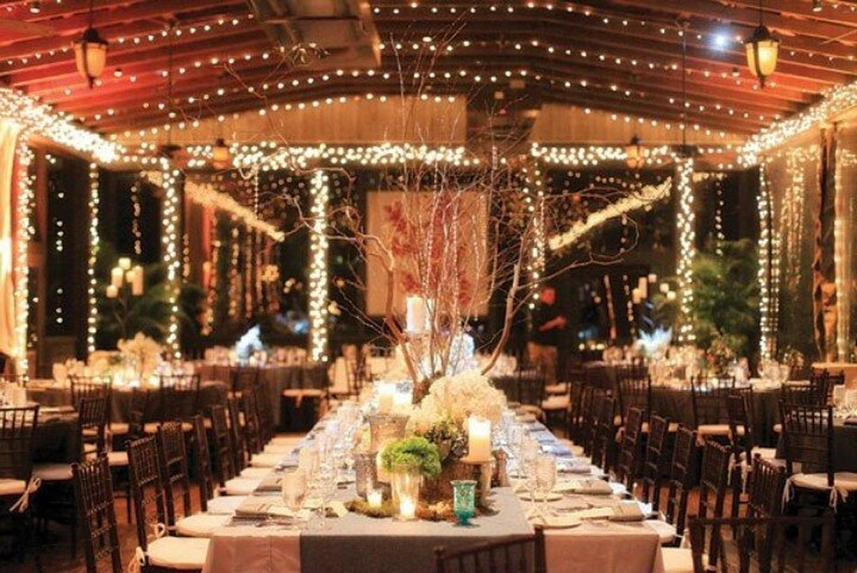 An elegant indoor venue for fall wedding with lighting, shape of tables, style of chairs, and linens and paper lanterns, trees and plants to your wedding room.