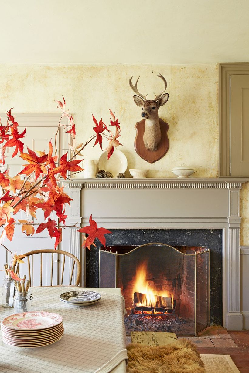 An extraordinary indoor redecoration from summer to fall with fireplace, wooden table, simple vase and wall decoration