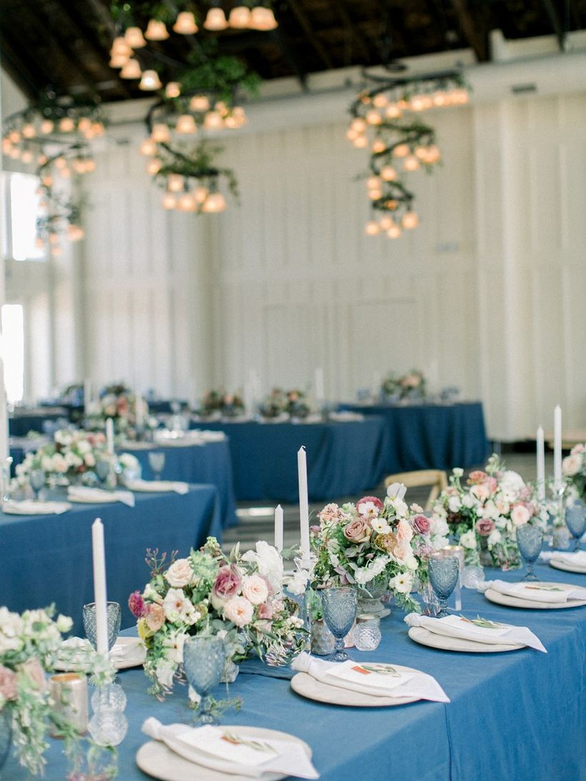 An impressive indoor table set for wedding with long tables feel dramatic and interesting with colored linens in surprising palettes instead.