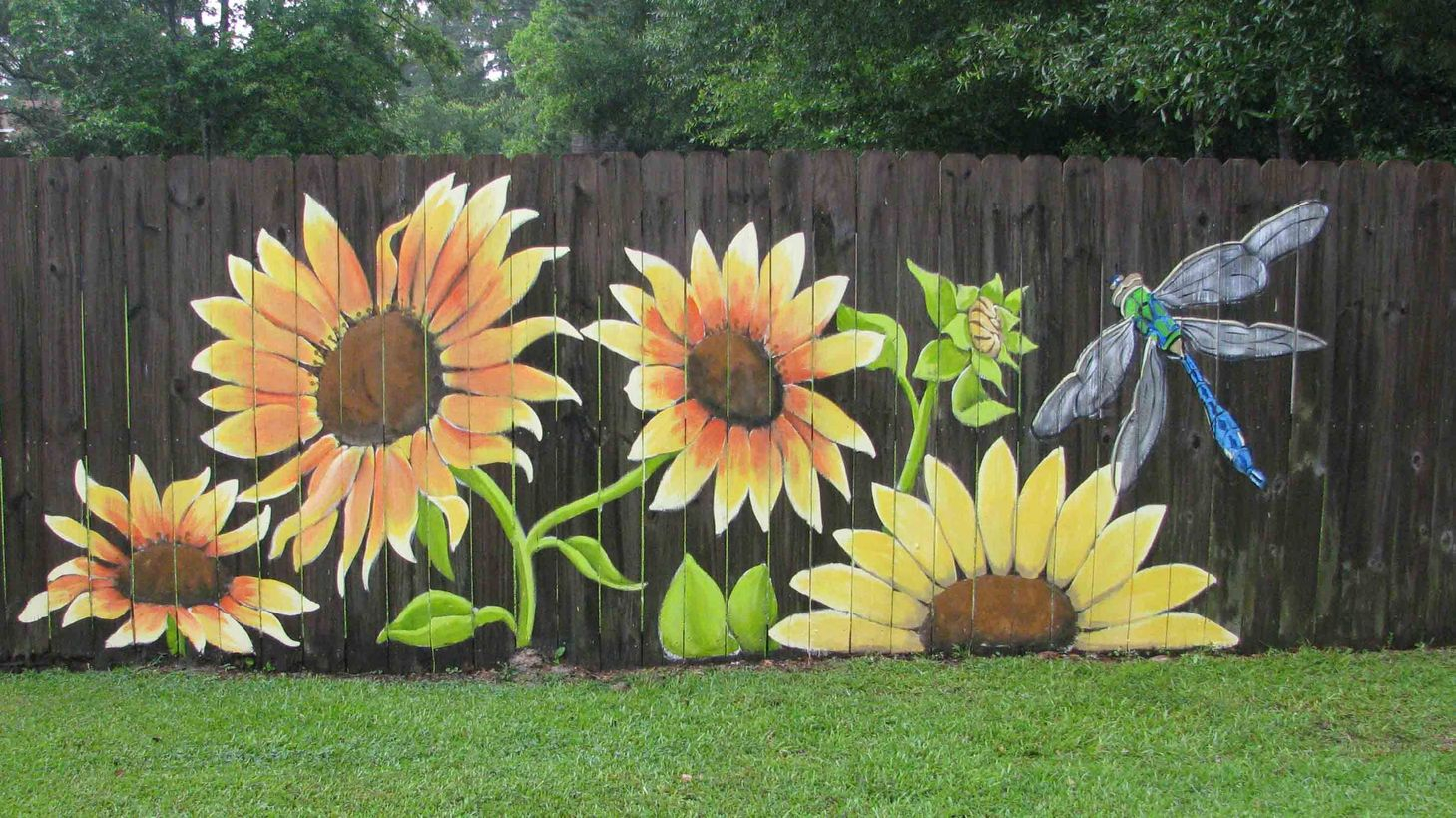 An incredible painting fence for garden with full sunflowers and dragonflies that get a look that’s bright and cartoon inspired but still with a little bit of impressive detail for balance.