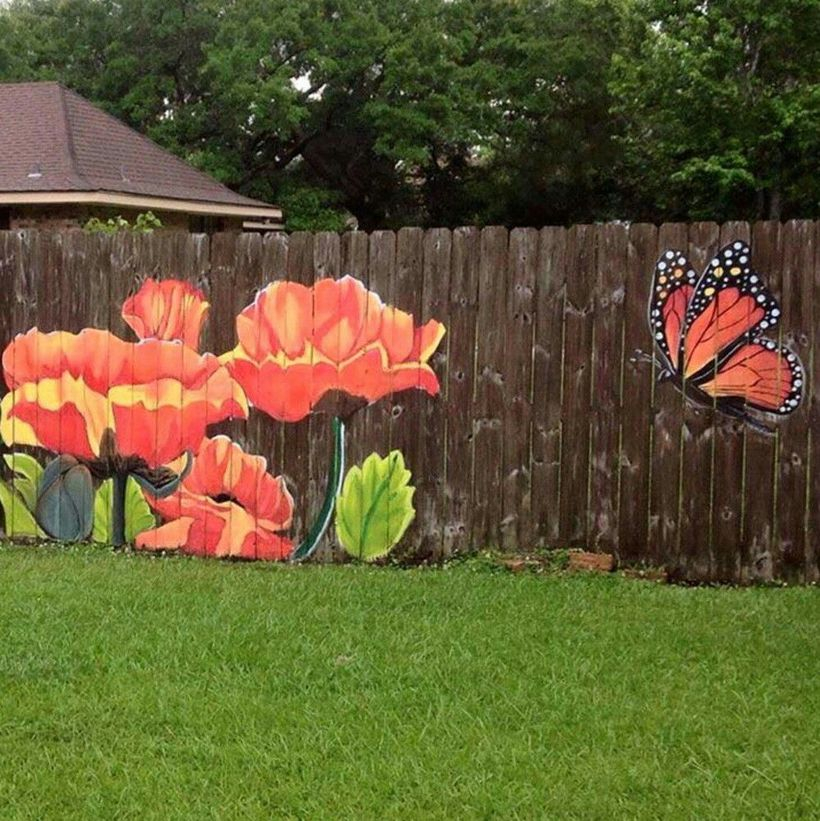 An interesting painting fence for garden with flowers and a monarch butterfly making its way over to some bright garden blossoms.