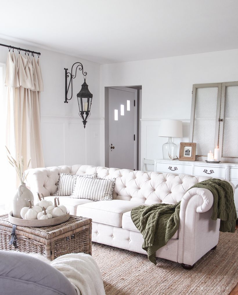 Modern farmhouse white living room with pumpkin decoration on rattan table coffee, white sofa, and hanging lamps to look rustic