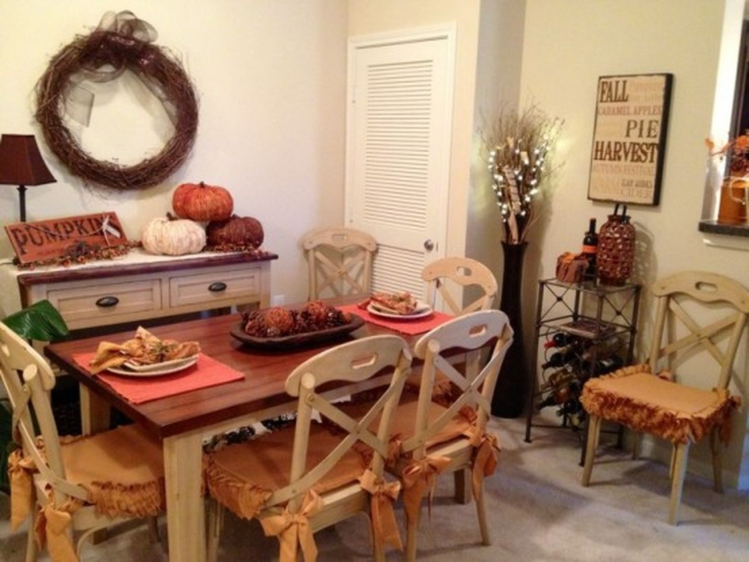 Rustic fall dining room decor ideas with pumpkin decoration on white table and wreath on the wall