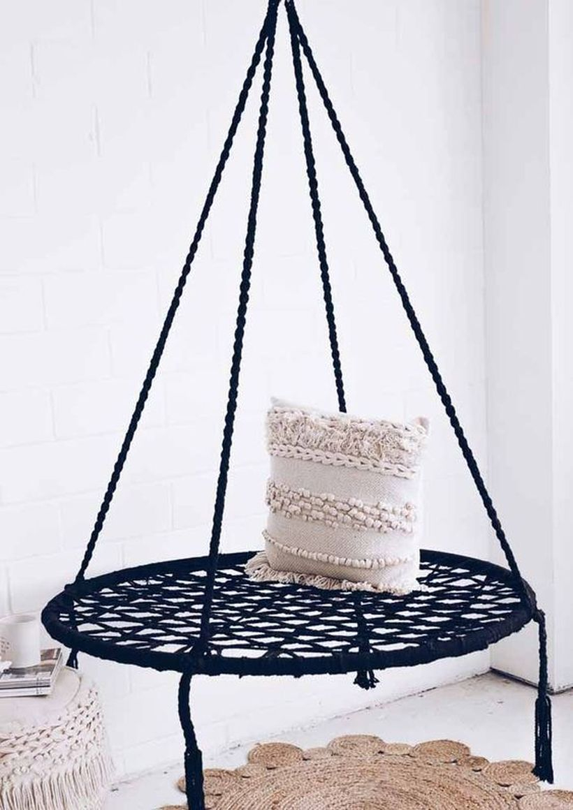 A black macrame boho seat with a boho pompom pillow.