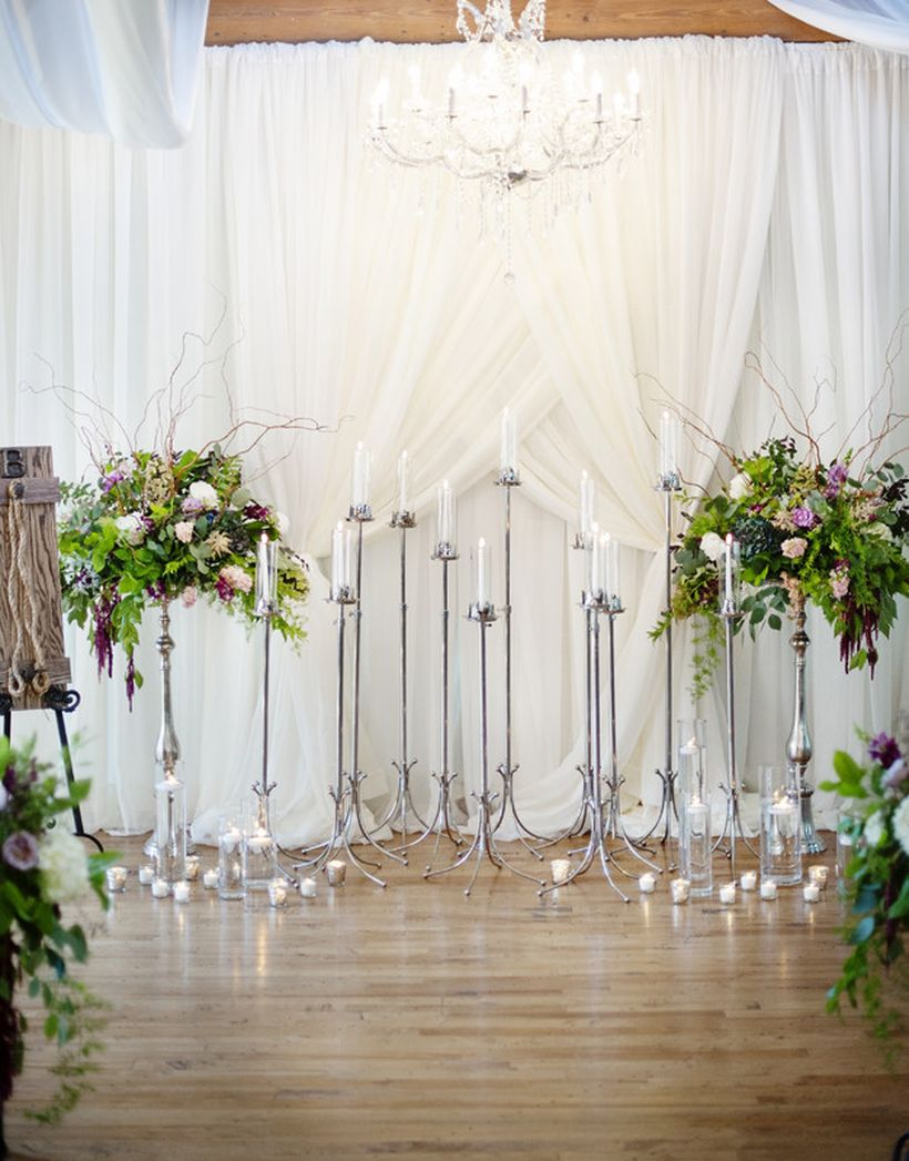 A dramatic backdrop created using floor candelabras, fabric draping and floral arrangements brings a european wedding feel to your ceremony