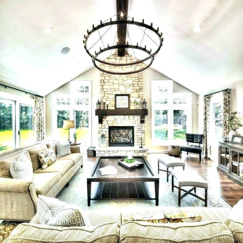 A fabulous rustic chandelier for living room with large round chandelier, patterned sofas, black wooden table, large carpet, a fireplace and large glass wall.