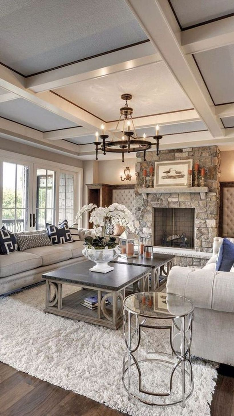 A stunning rustic chandelier for living room with round wooden rustic chandelier, grey sofa, black tables, white rug, big windows and decoration on the table.