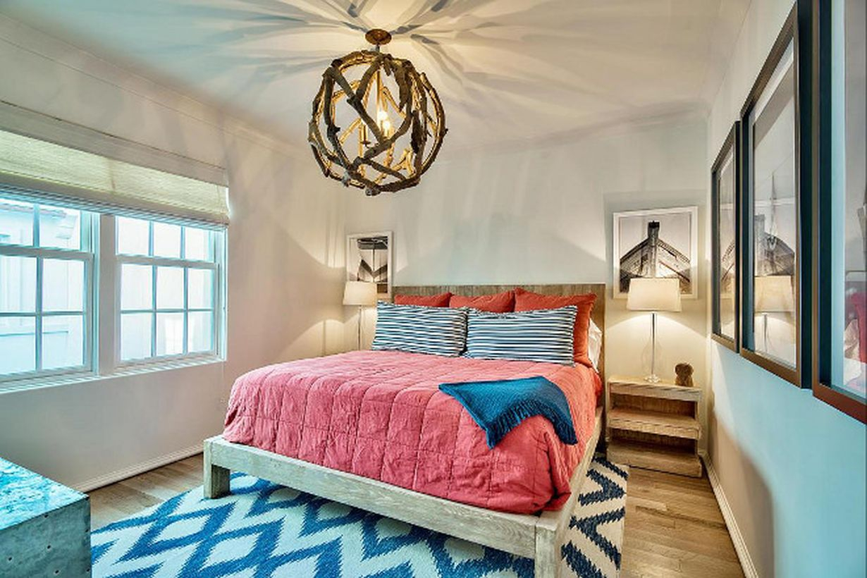 A unique rustic chandelier for bedroom with florida chandelier, pink bed linen, patterned carpet, small table, wooden floor and windows large.