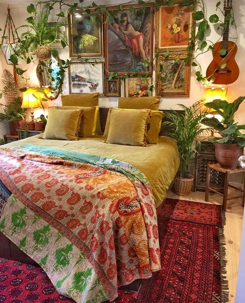 An awesome boho bedroom style with colorful patterned blankets, yellow bed combined with red patterned carpets, wall paintings, and plants as room fresheners