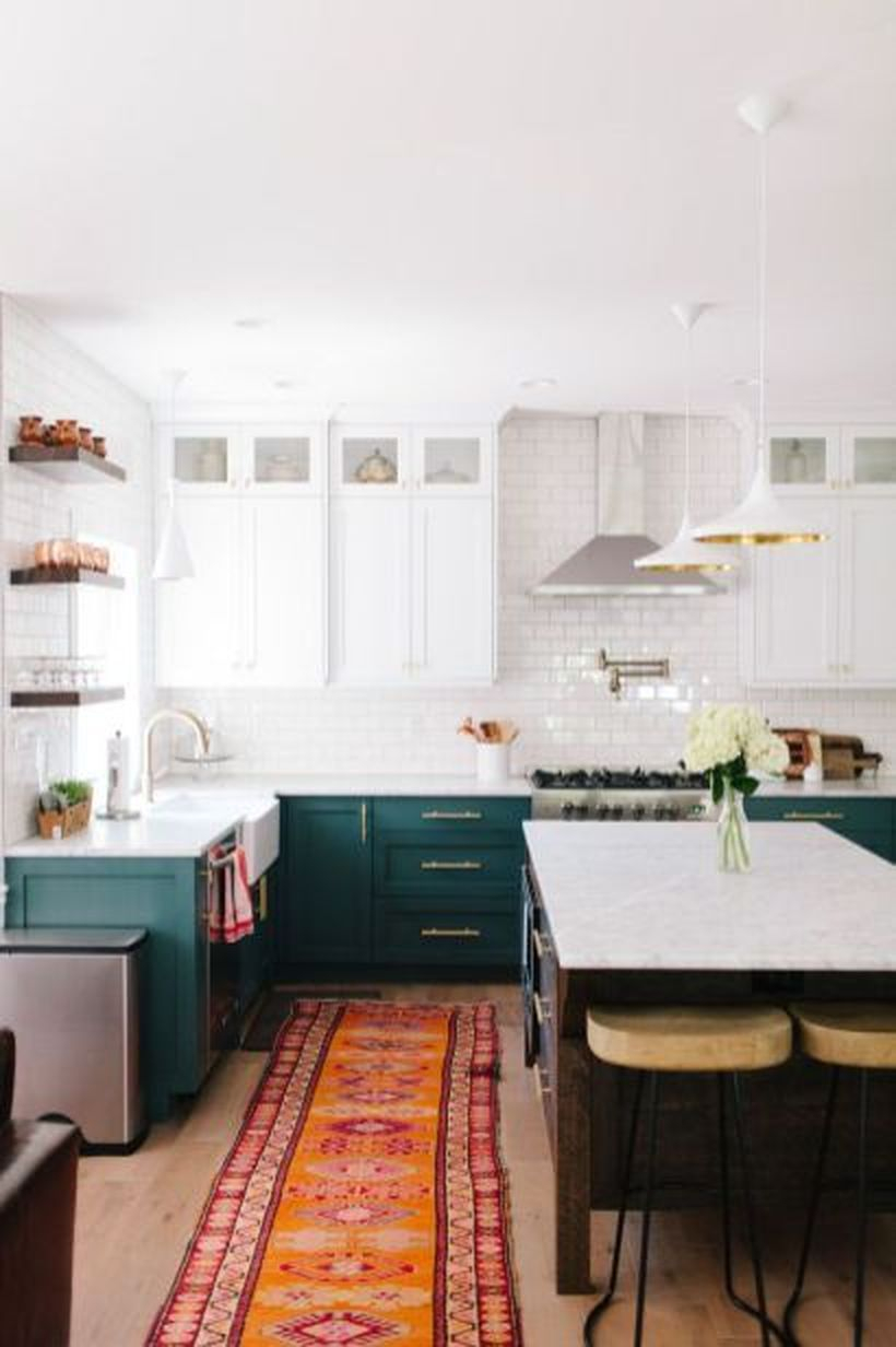 An awesome boho kitchen decor with long orange pattern carpet, green storage cabinet, white walls and island table made of wood to look good