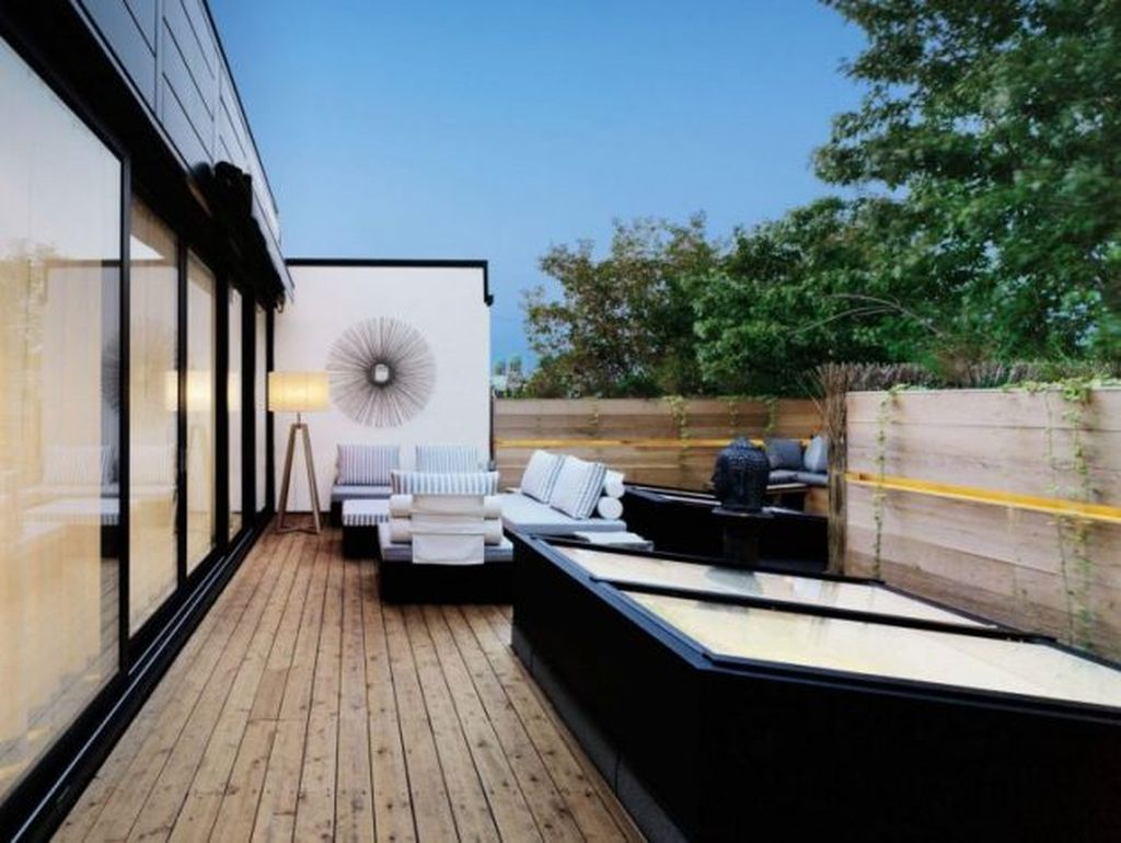 An amazing rooftop design with striped sofa combined with wooden floor and wooden fences to perfect your rooftop garden design
