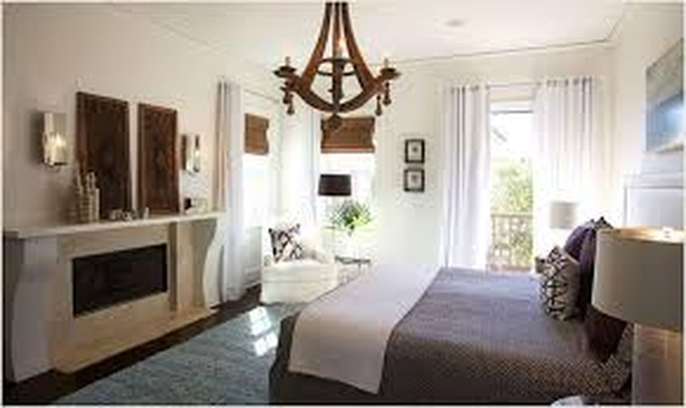 An amazing rustic chandelier for bedroom with laurel foundry chandelier, white chair on the corner, big windows, long white curtain, white blanket and decoration on the wall.