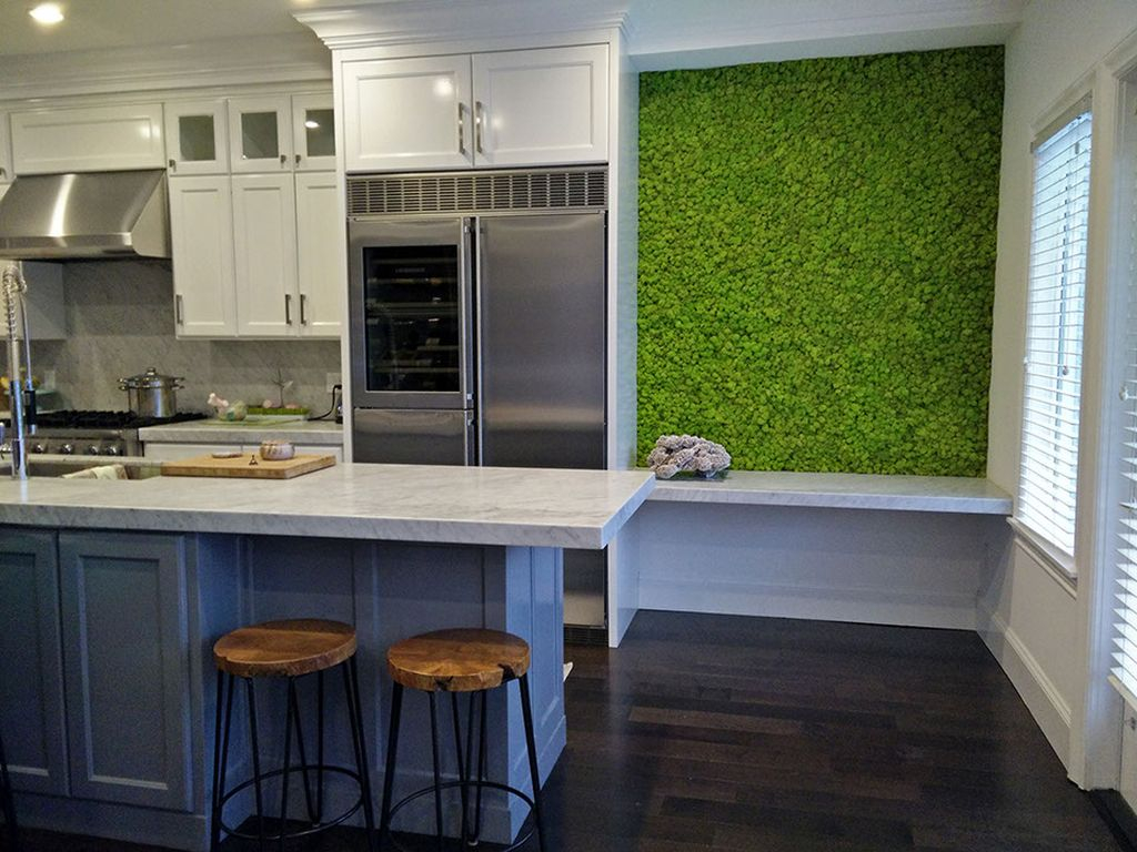 An elegant kitchen design with white cabinets and dark floor combined with moss wall to make impression nature in the kitchen