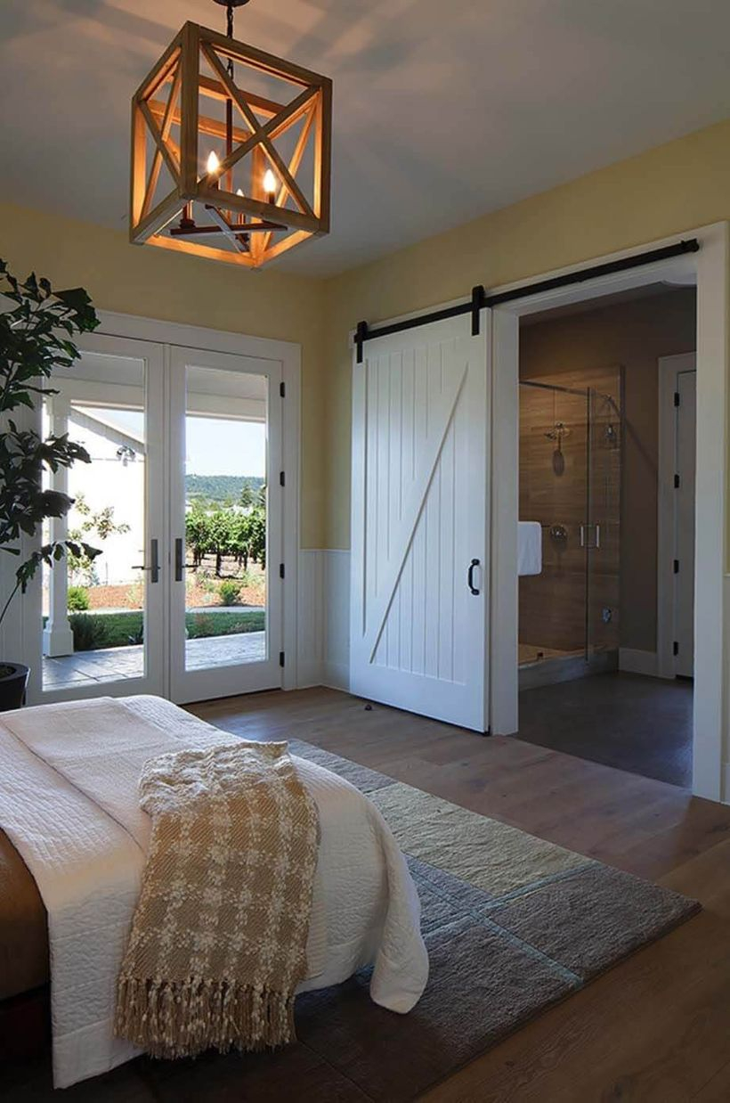 An extraordinary rustic chandelier for bedroom with edison’s manor chandelier, sliding wooden door, house plant, large carpet, wooden floor, a white blanket and wooden floor.