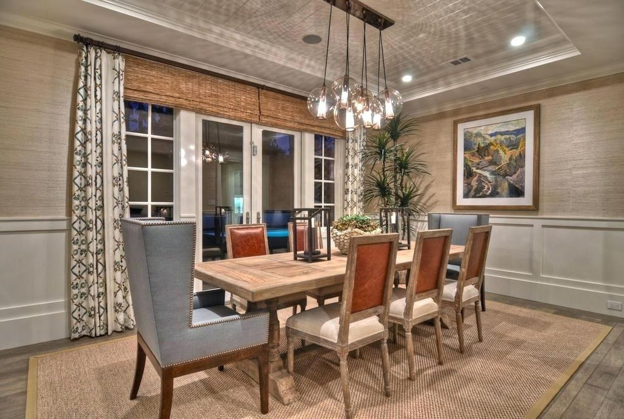 An impressive rustic chandelier for dining room with over pendant chandelier, a wooden table, wooden chairs, a large carpet and a long curtain.