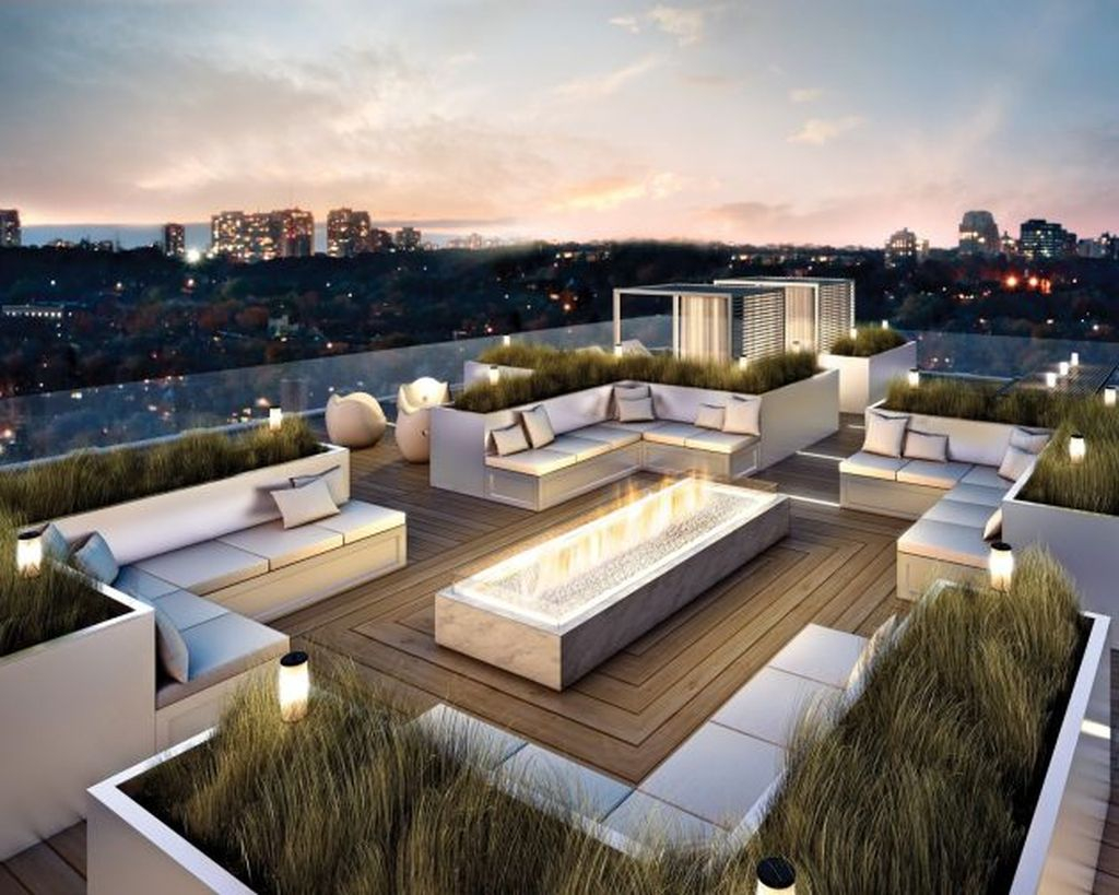 Beautiful modern small rooftop design with letter l sofa combined with wooden floor, fireplace in the middle and plants around it to perfect your rooftop garden